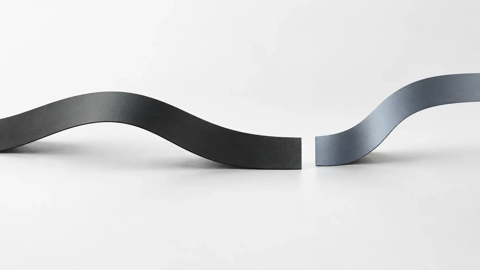 A charcoal ribbon ends at a clean break, with a blue-grey ribbon curving away beyond the gap.